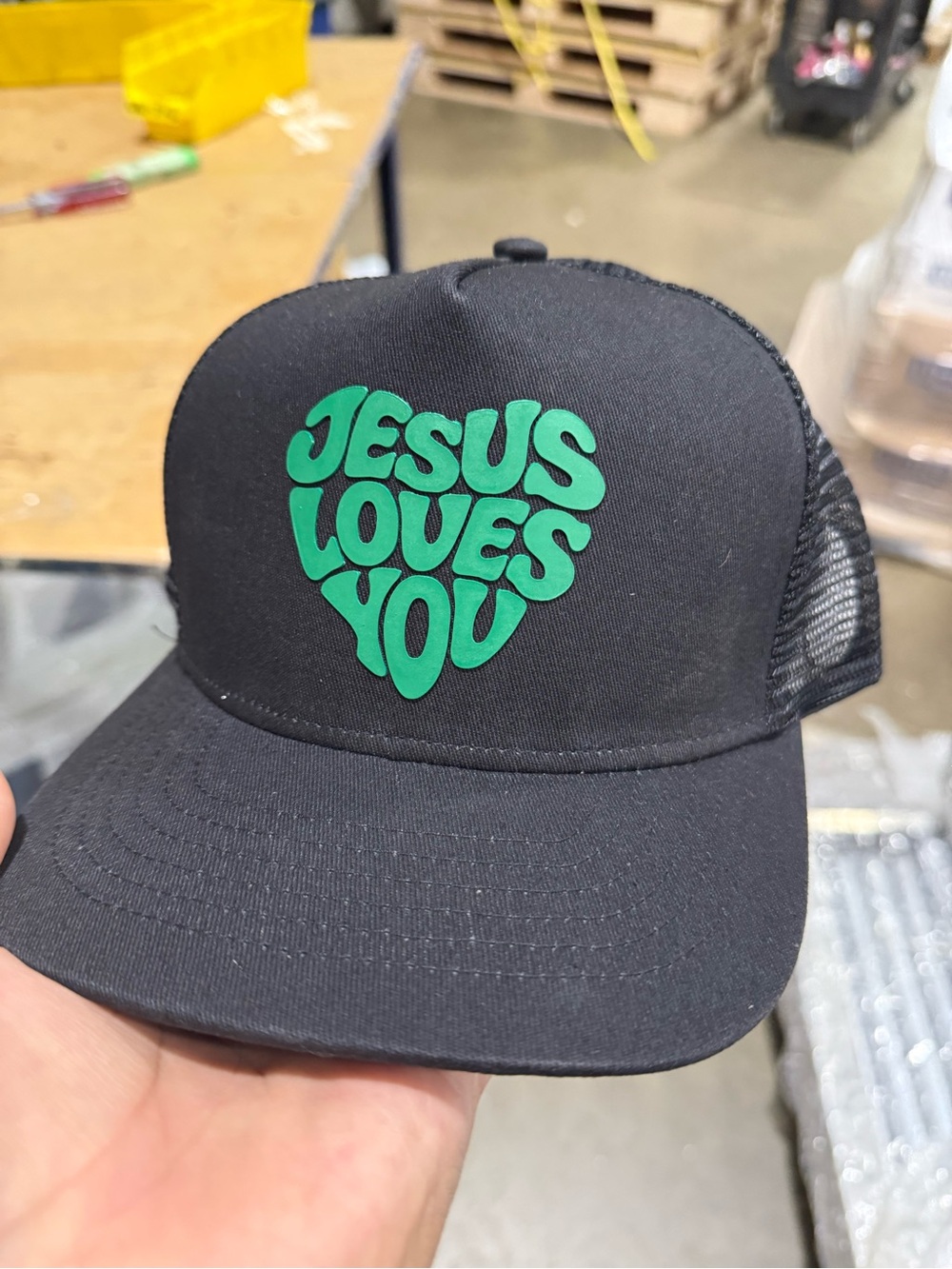 Black Trucker Hat with Green "JESUS LOVES YOU" Heart Graphic